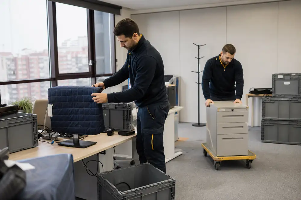 Profesionales trasladan mobiliario y equipos en una oficina